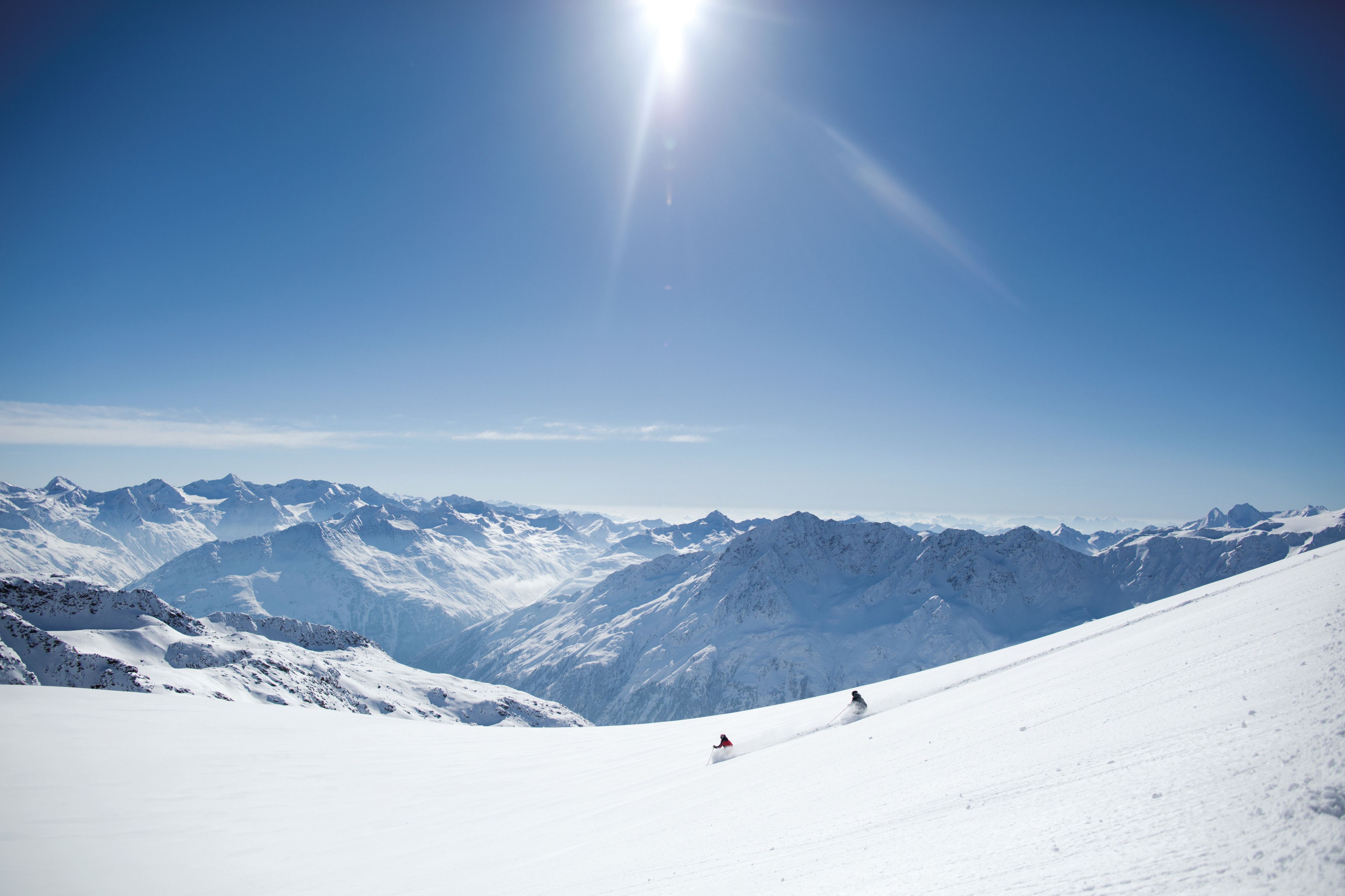 A snowy mountain landscape with a clear sky and distant peaks.