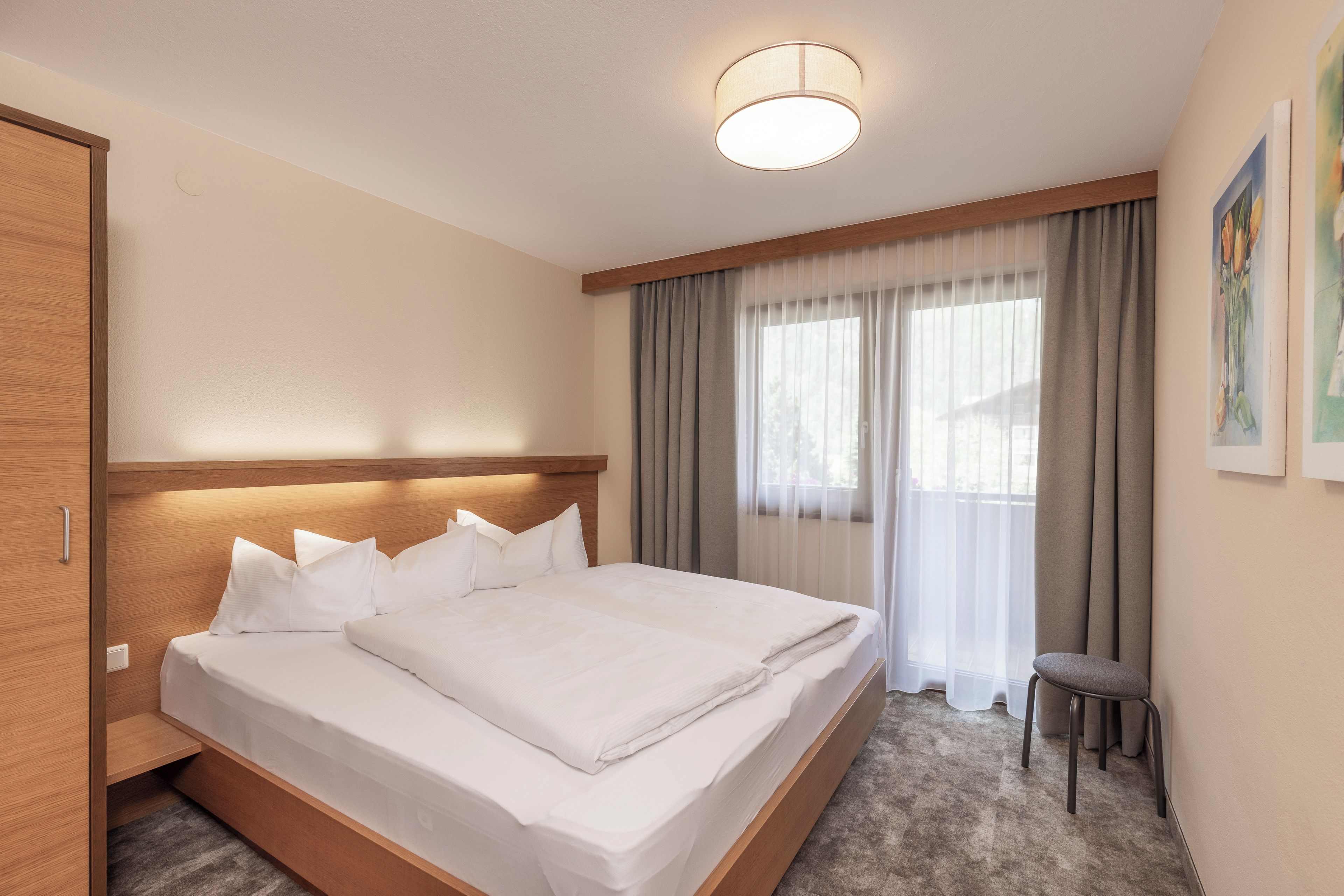 A hotel room with a bed, a desk, and a window with curtains.