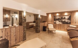 Ett spa-rum med träpanel, en massagebänk, en massagestol och ett stort fönster med utsikt över bergen.
