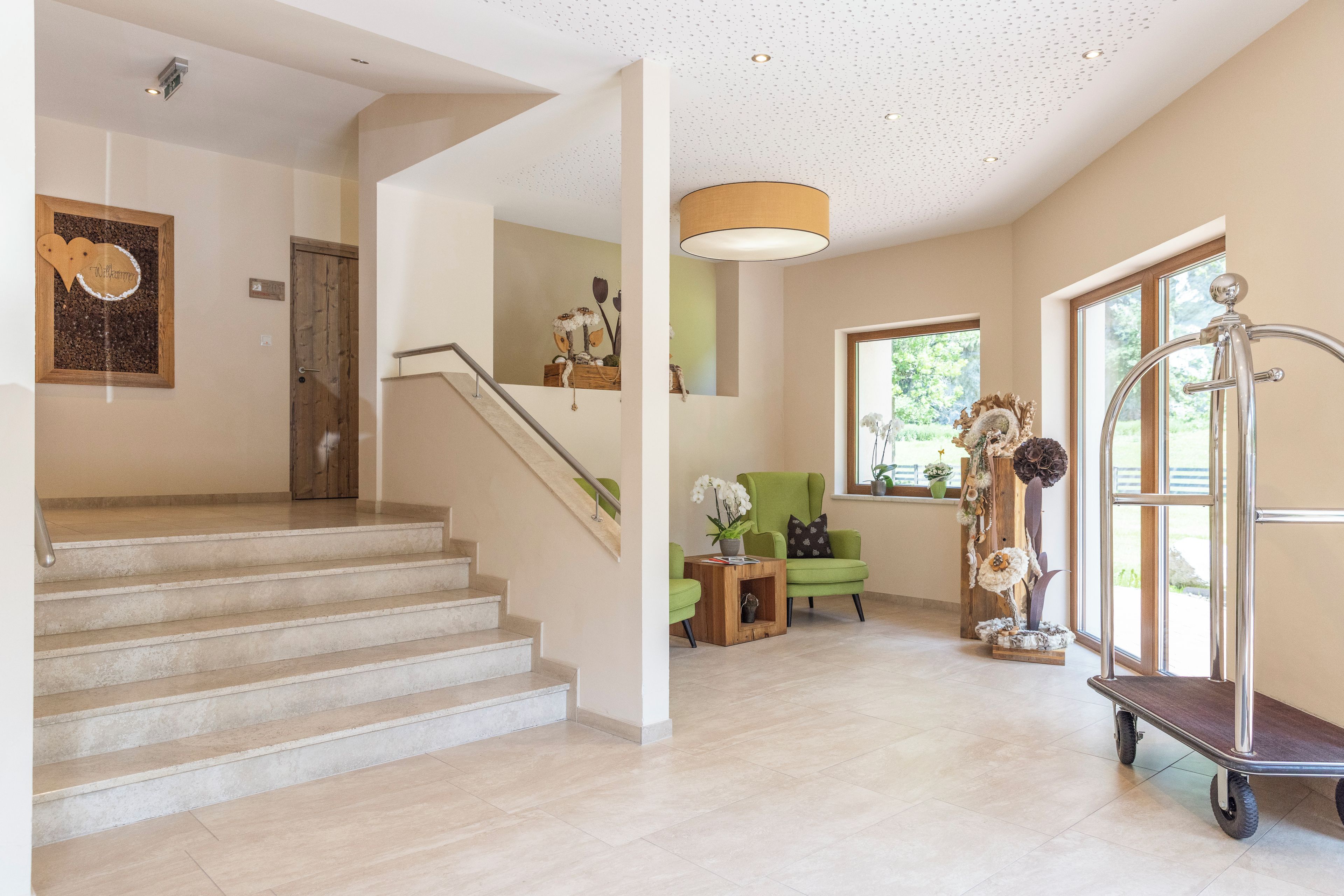 A staircase leading to a landing with a wooden door, a green armchair, and a decorative plant arrangement.