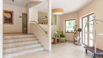 A staircase leading to a landing with a wooden door, a green armchair, and a decorative plant arrangement.