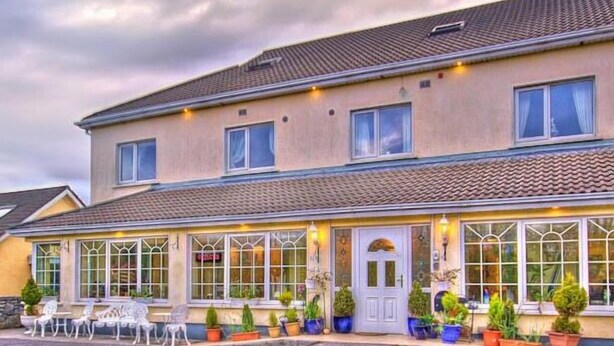 A two-story building with a tiled roof, large windows, and outdoor seating. - Teach na Coiribe (Galway)