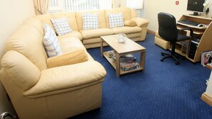 A living room with a beige sofa, a coffee table, and a TV. - Teach na Coiribe (Galway)