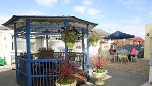 A gazebo with a blue frame and a table underneath, surrounded by potted plants. - Teach na Coiribe (Galway)