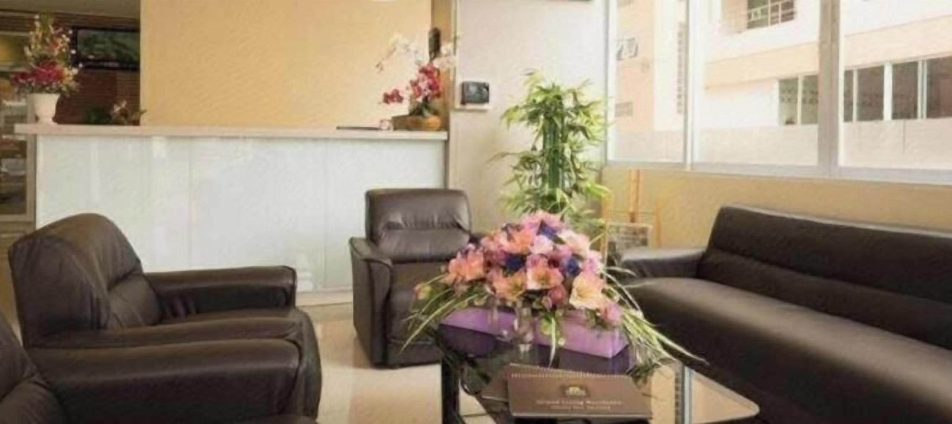 Un área de recepción con una mesa de recepción, dos sofás de cuero y un jarrón con flores.