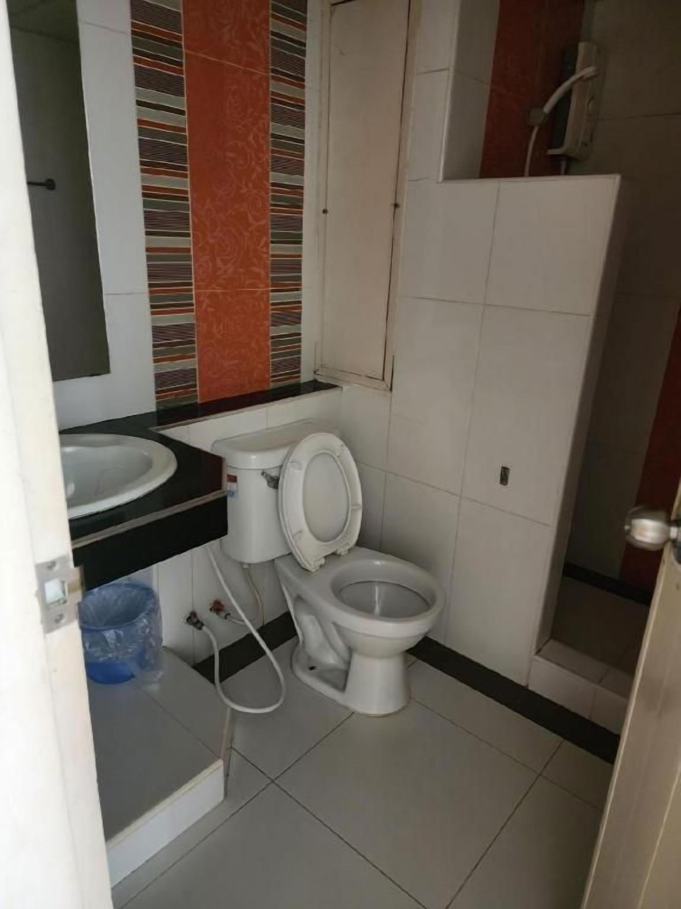 A bathroom with a toilet, sink, and a mirror.