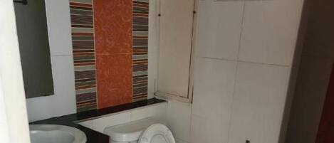 A bathroom with a toilet, sink, and a mirror.