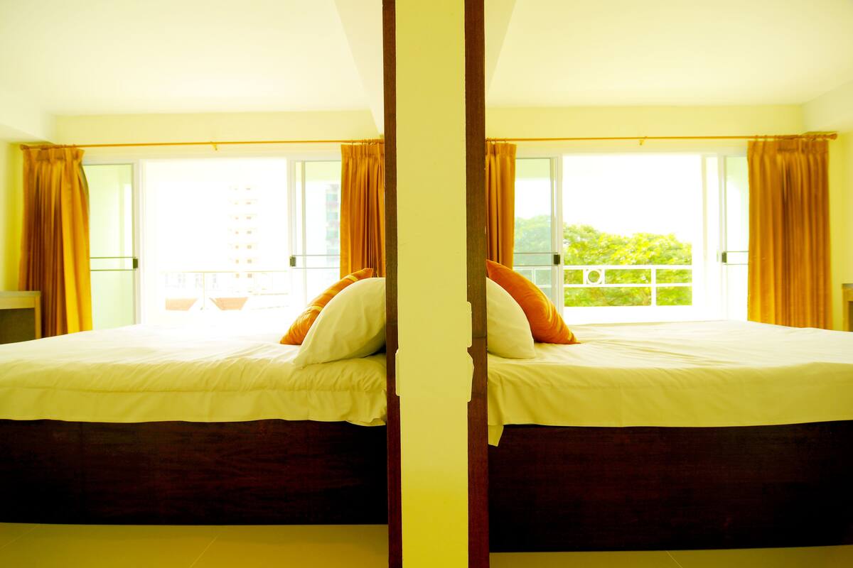 A mirrored room with a bed, curtains, and a balcony with a view.
