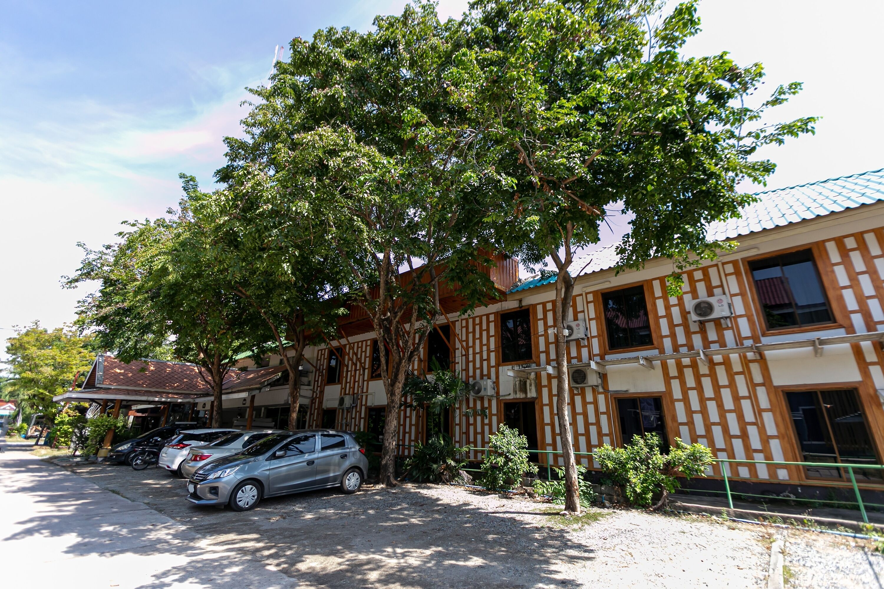 Un edificio con estilo arquitectónico tradicional, que combina elementos de madera y concreto. Varias automóviles están estacionadas a lo largo de la calle frente al edificio.