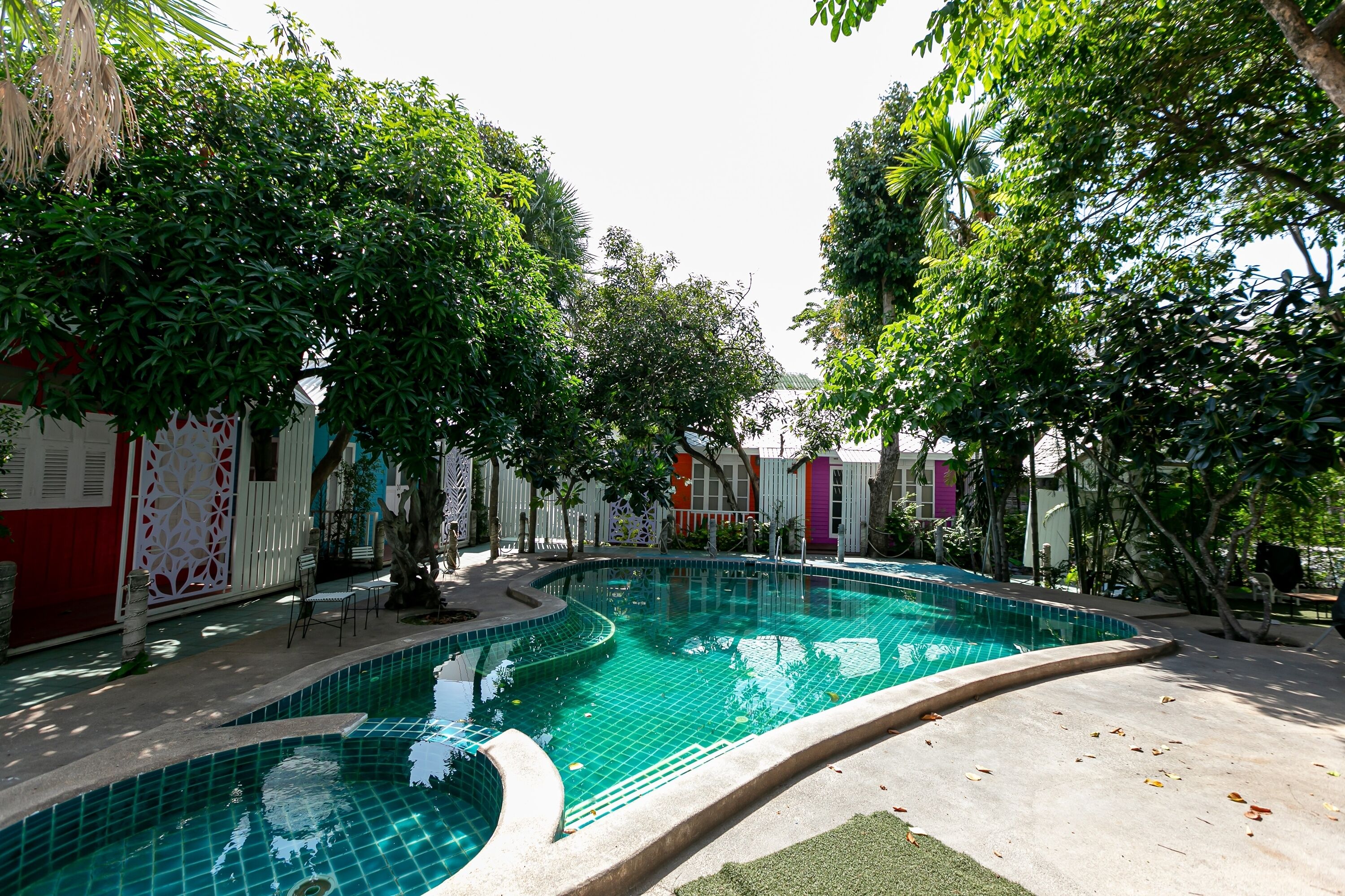 Piscina cercada por árvores e edifícios coloridos.