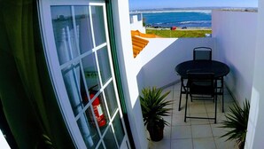 A balcony with a view of the ocean, a table with chairs, and a fire extinguisher. - Peniche Surf Lodge - Hostel (Peniche)