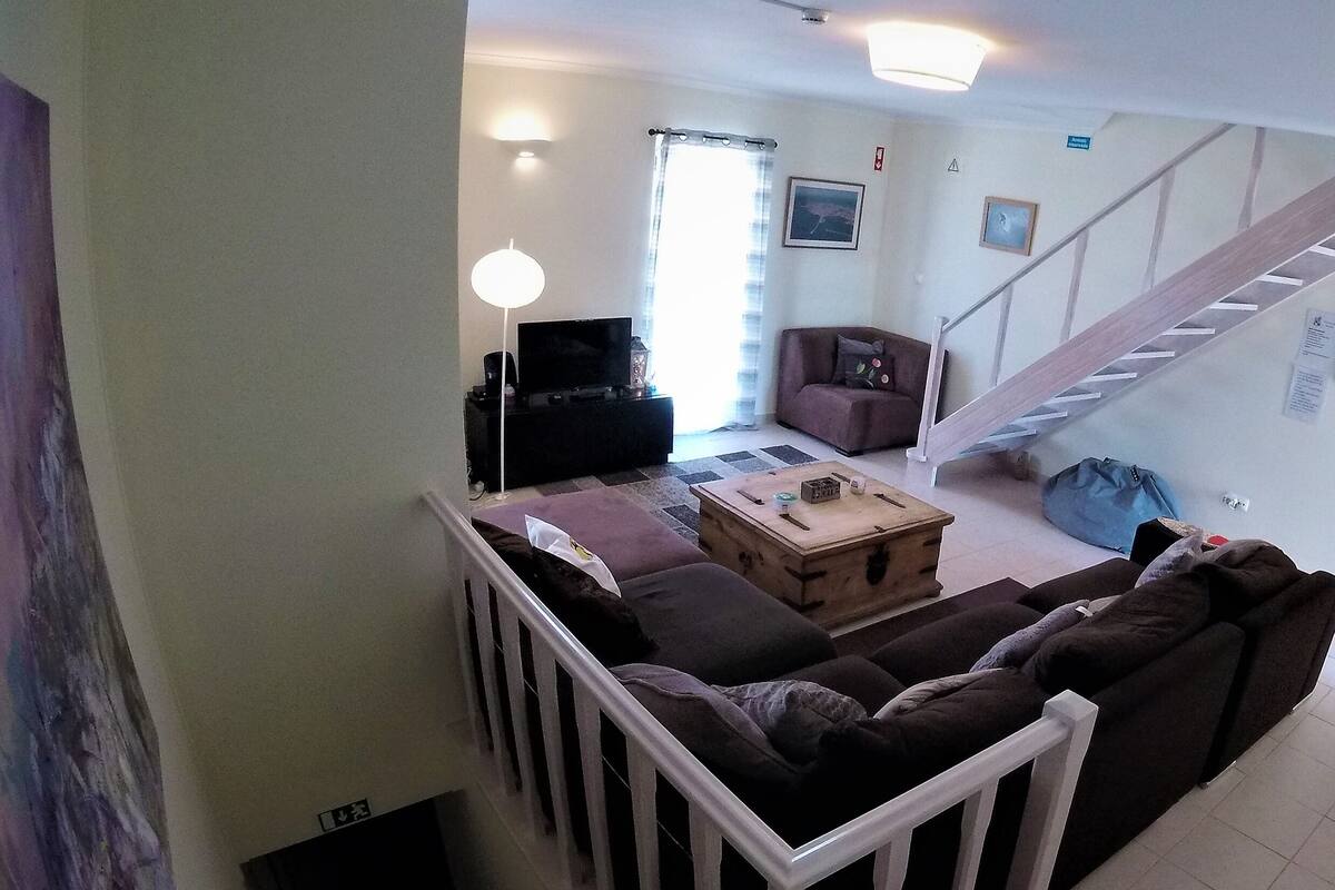 Una sala de estar con un sofá, una mesa de centro, un televisor y una escalera.
