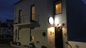 A two-story building with a balcony, a lit entrance, and a number 6 door. - Peniche Surf Lodge - Hostel (Peniche)