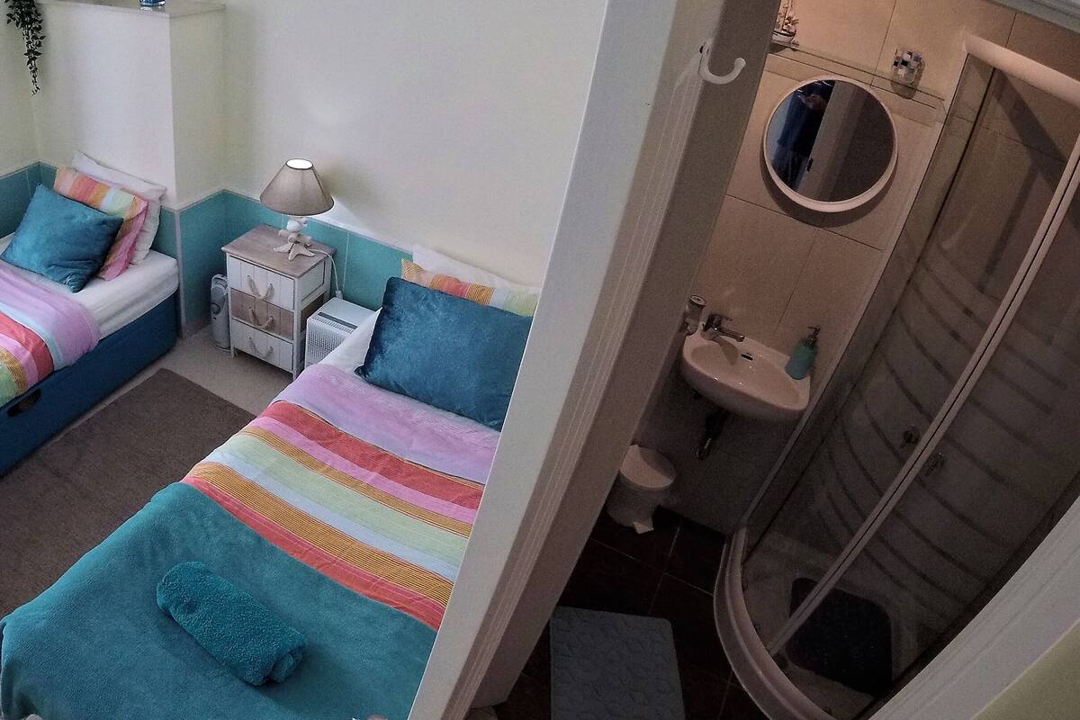 Un dormitorio con cama, mesita de noche, lámpara y una ventana pequeña.