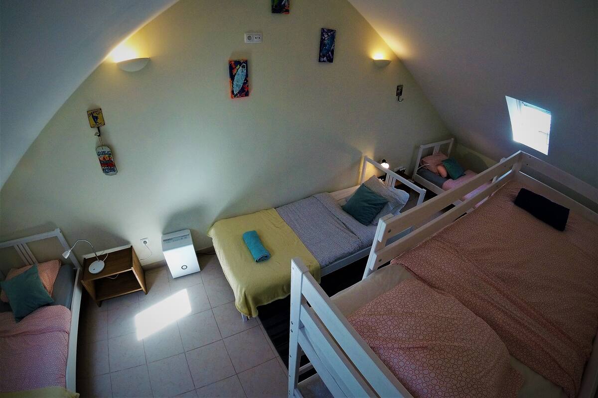 Un dormitorio con dos literas, un escritorio y un ventanal pequeño.
