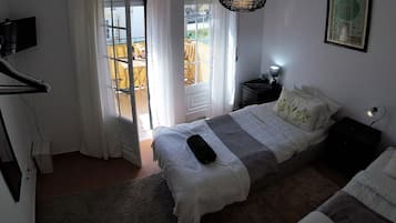 A bedroom with a bed, bedside table, lamp, and a view of the outdoors through a window.