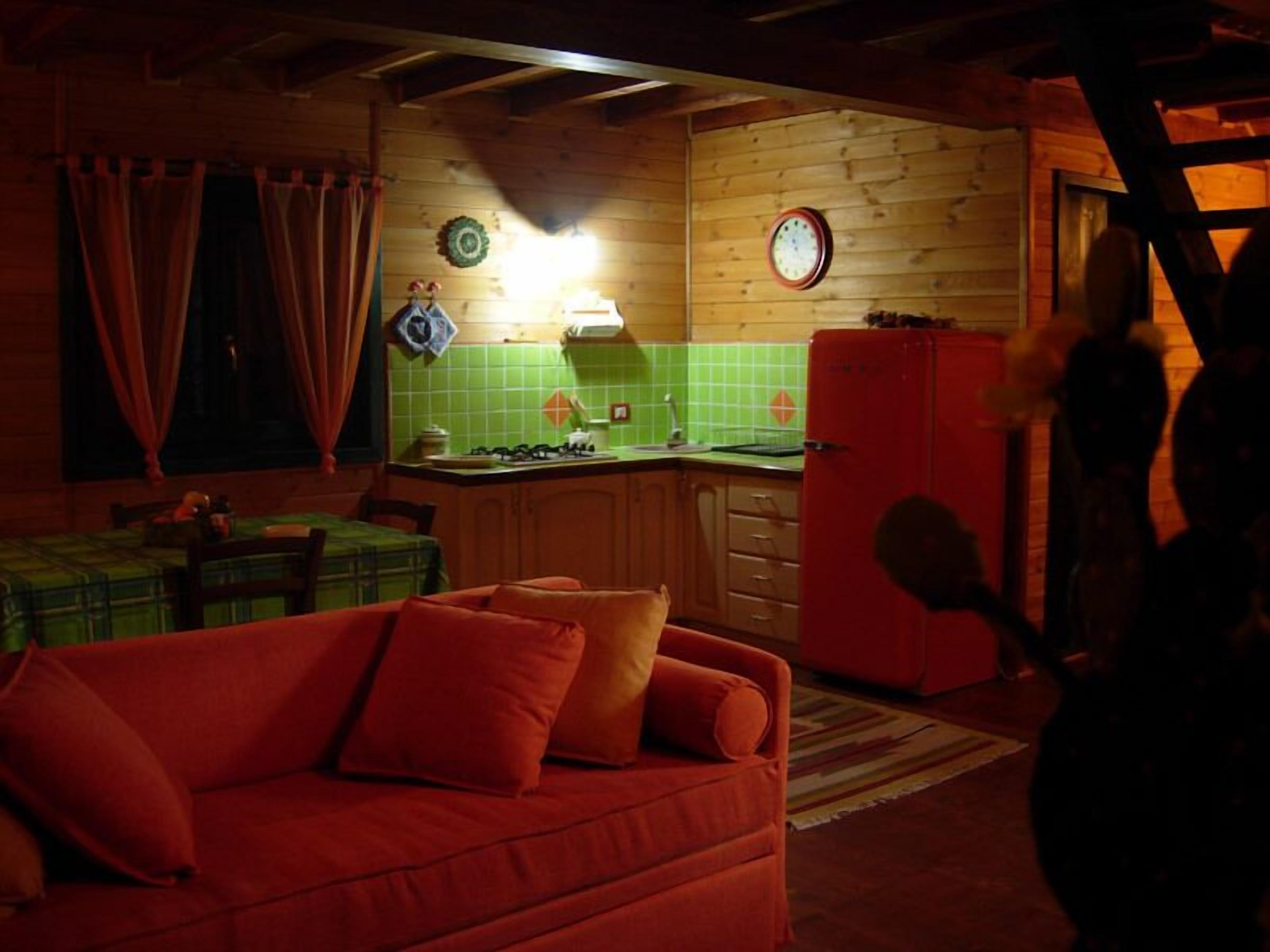 L’intérieur chaleureux d’un chalet avec un décor en bois, un coin repas, une cuisine dotée d’un réfrigérateur rouge et un salon avec un canapé rouge.