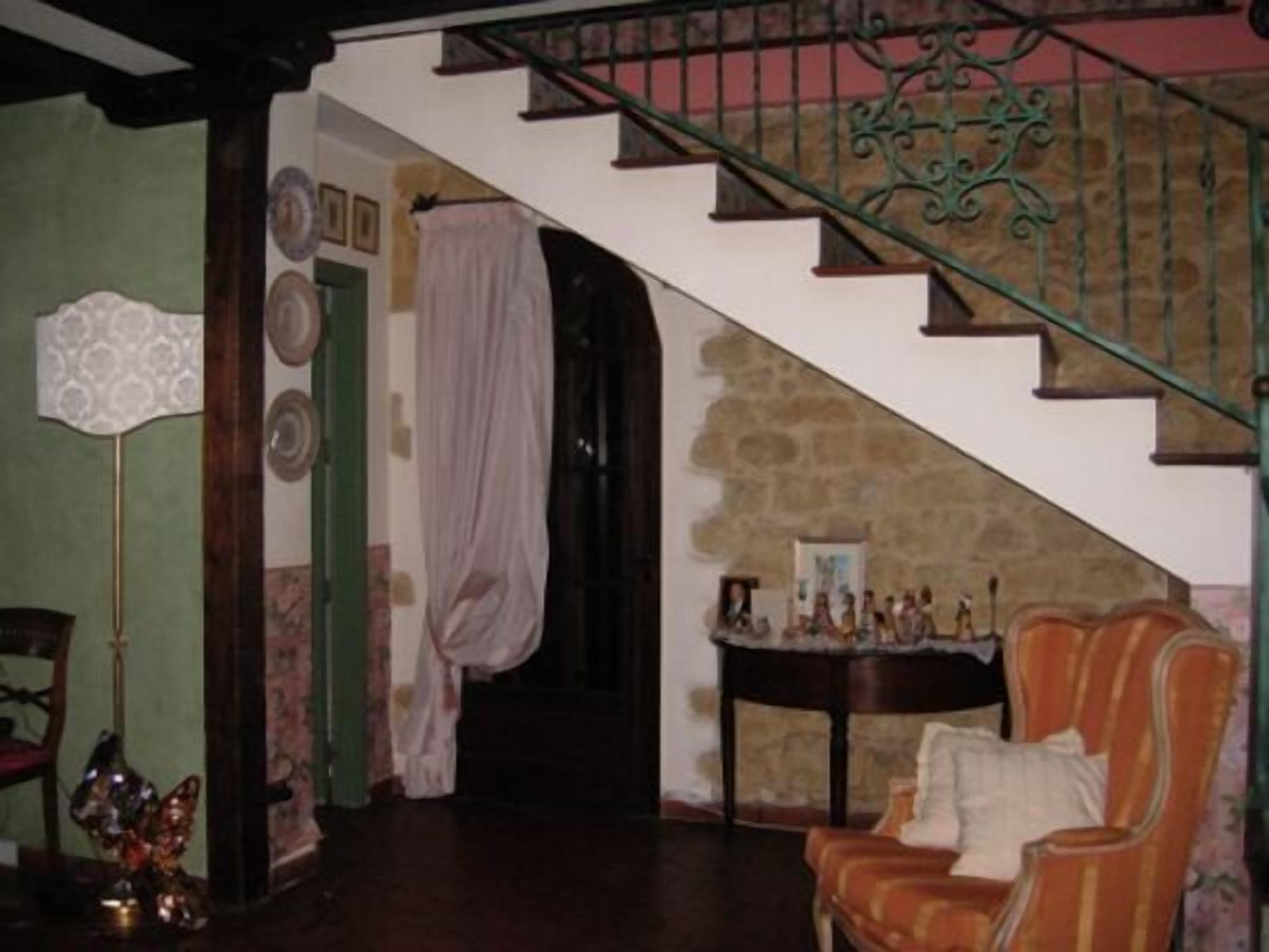 A staircase with a green metal railing, a stone wall, and a small table with decorative items.