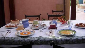 Una mesa lista para el desayuno, con platos, tazas y una tetera.