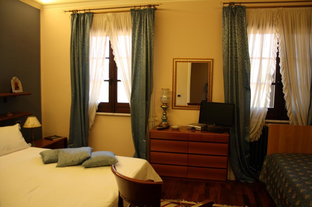 Un dormitorio con cama, cómoda, espejo y cortinas.