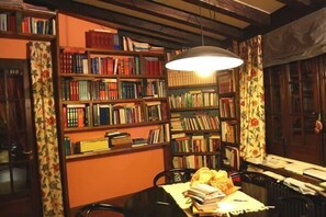 A room with a wooden table, chairs, and a bookshelf filled with books. - Villa Clementine (Piazza Armerina)