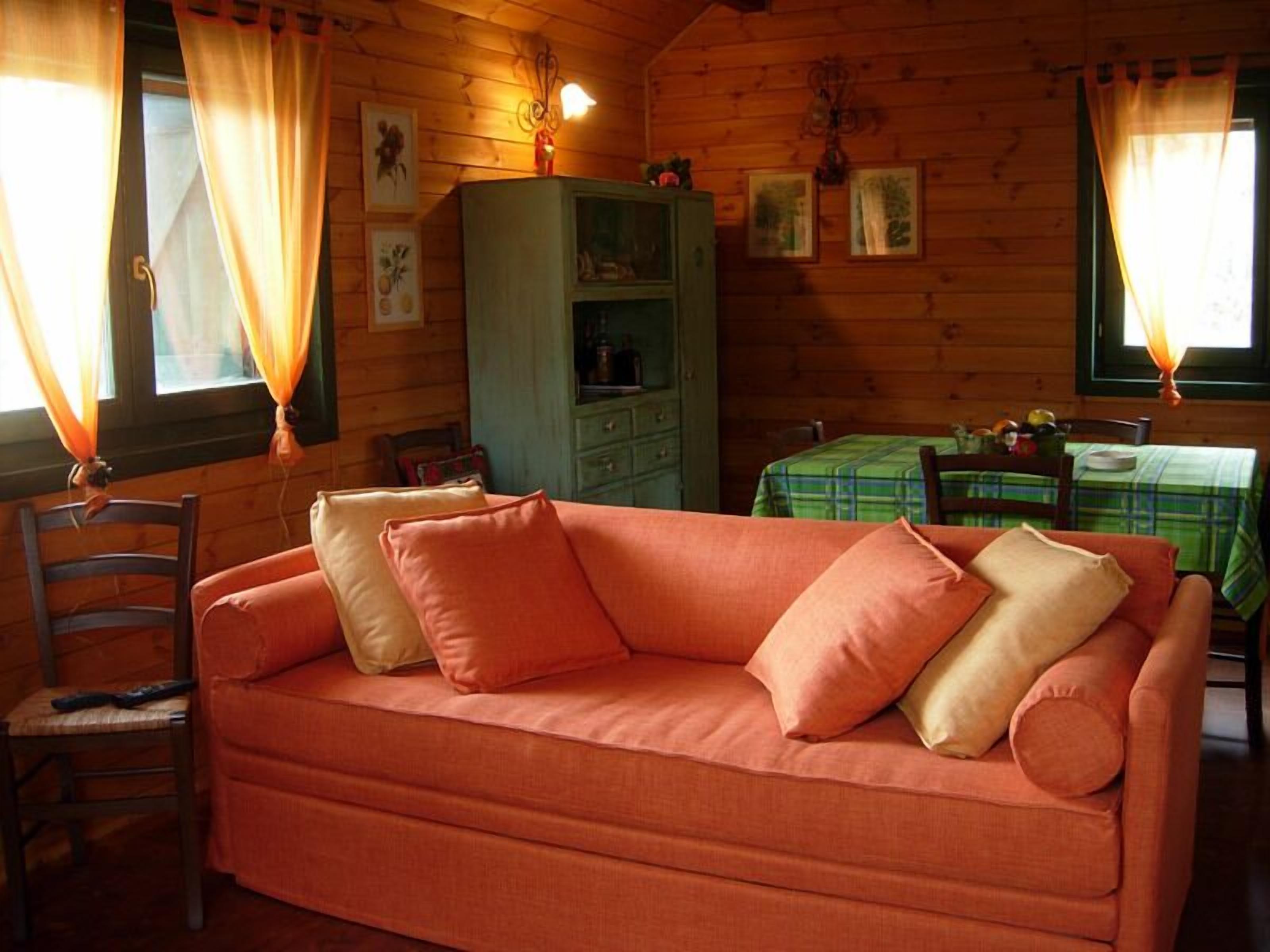 A cozy cabin interior with a sofa, a dining table, and a cabinet.