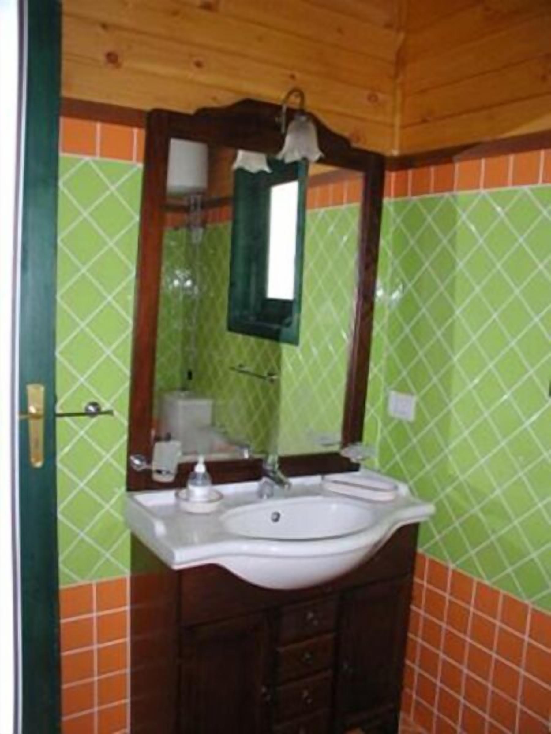 A bathroom with a white sink, a mirror, and a green tiled wall.