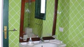 A bathroom with a white sink, a mirror, and a green tiled wall.