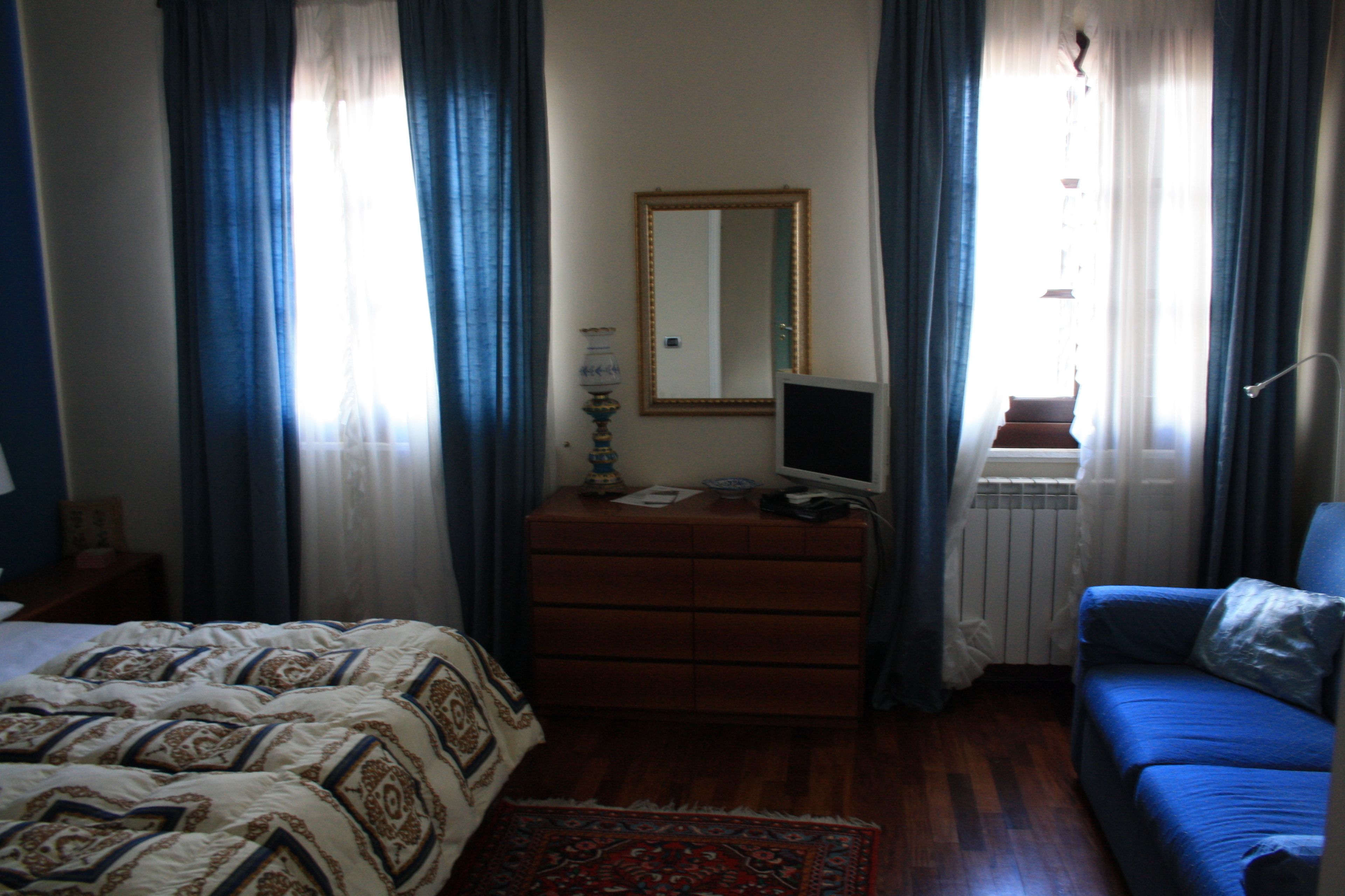 A bedroom with a bed, dresser, and blue sofa.