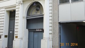 A building with classical architecture, featuring a prominent arched entrance and a balcony with a bird perched on it. - Luxury Oldtown Apartments (Vienna)