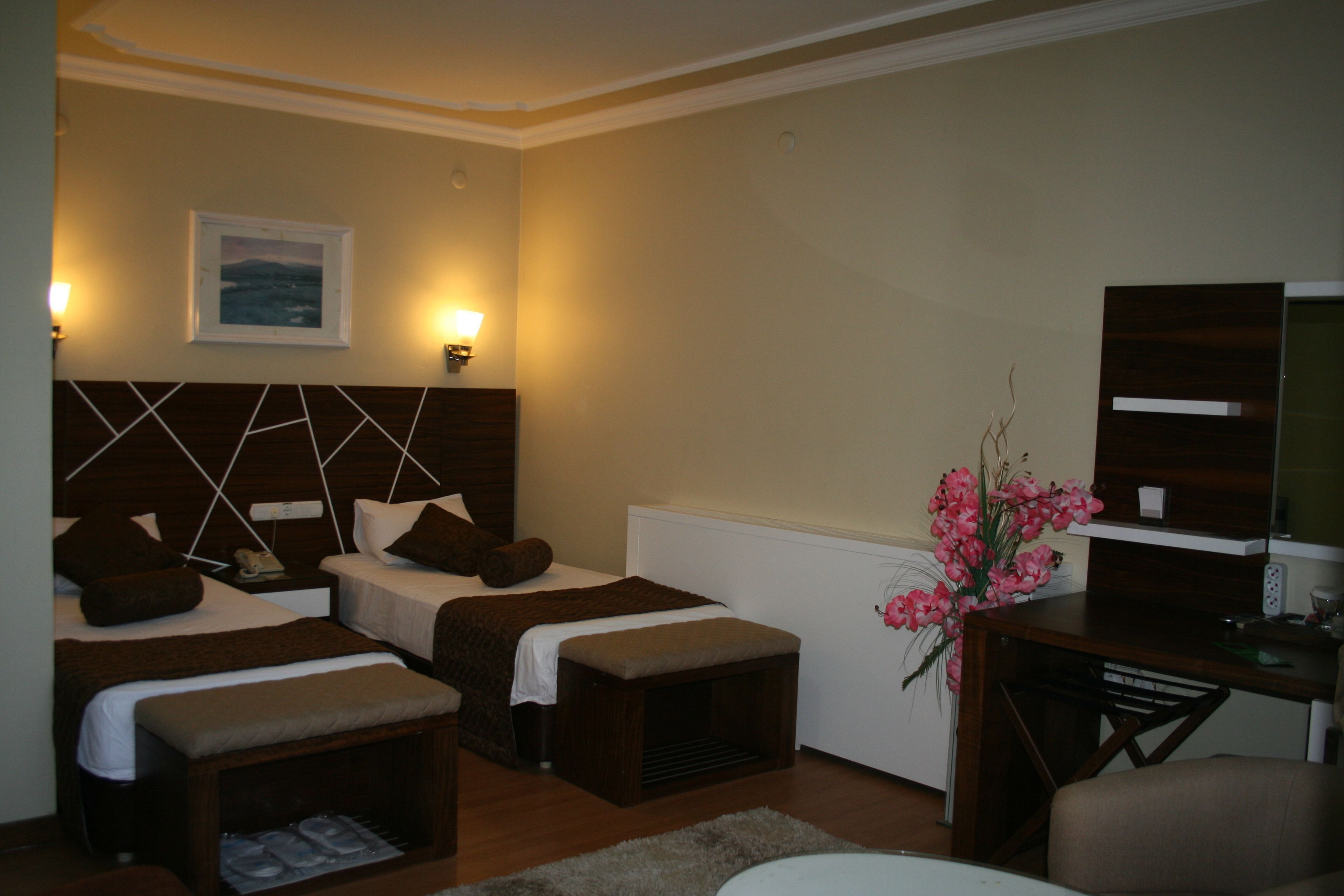 A hotel room with two beds, a desk, a chair, a TV, and a wall-mounted picture.