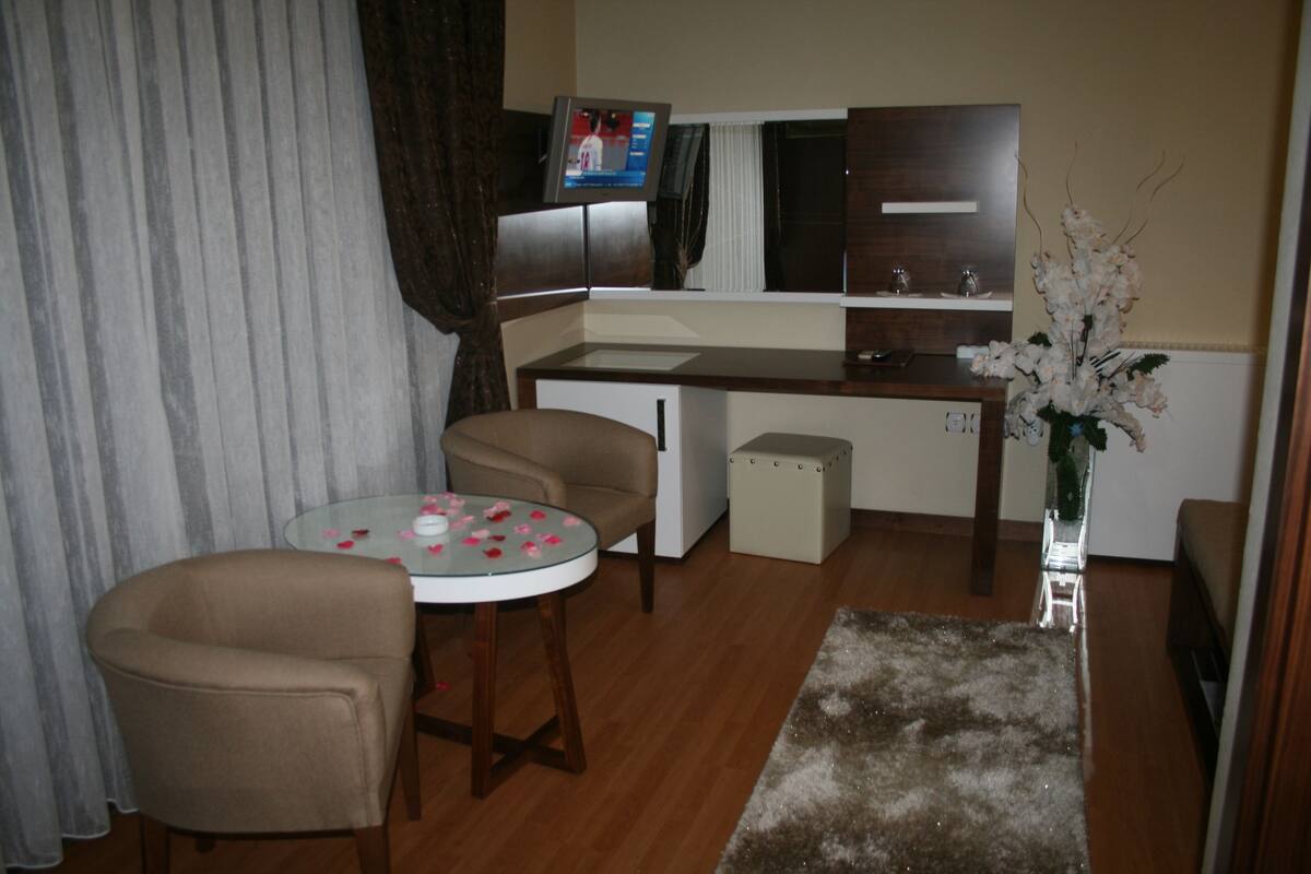 Un espacio habitable compacto con kitchenette, una zona de comedor con mesa de vidrio y un área de descanso con dos sillas.