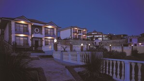 Un edificio residencial de varios pisos con fachada de piedra, varios balcones y una entrada bien iluminada.