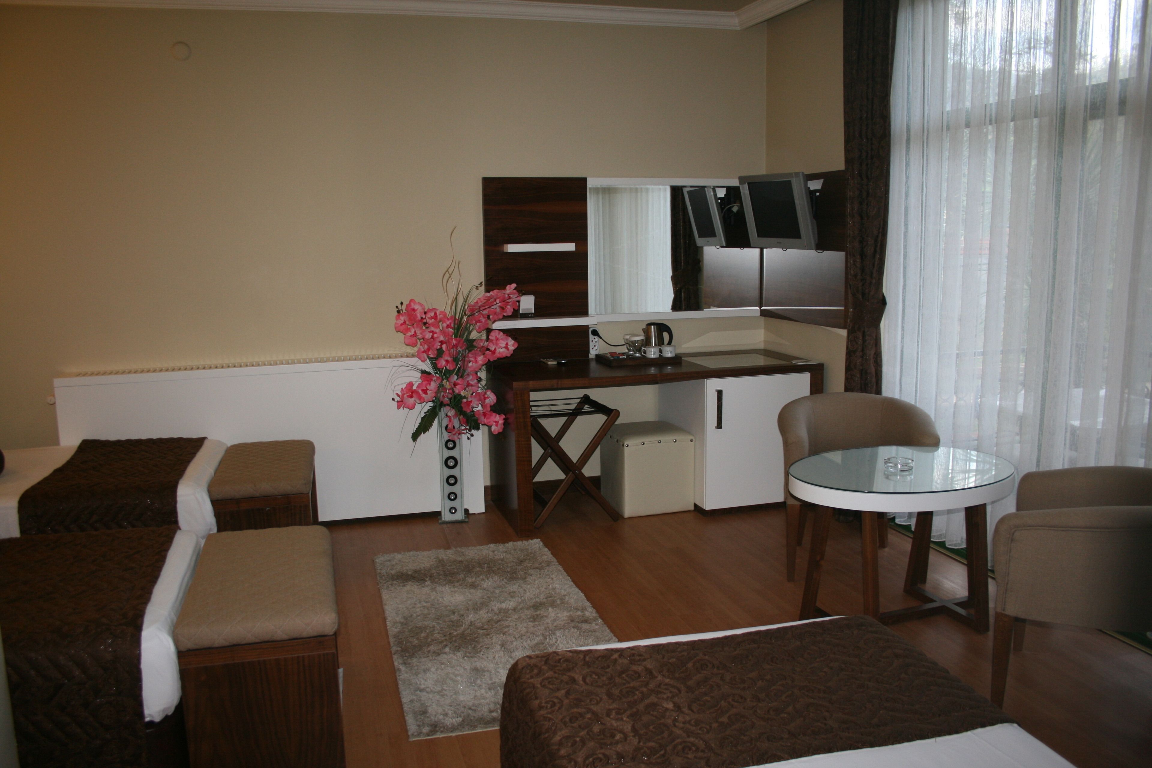 Een hotelkamer met kitchenette, een eethoek met glazen tafel, twee bedden en een klein zithoekje.