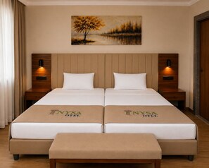 A double bed with a headboard, two bedside tables with lamps, and a painting above the bed. - Nysa Hotel (Sultanhisar)