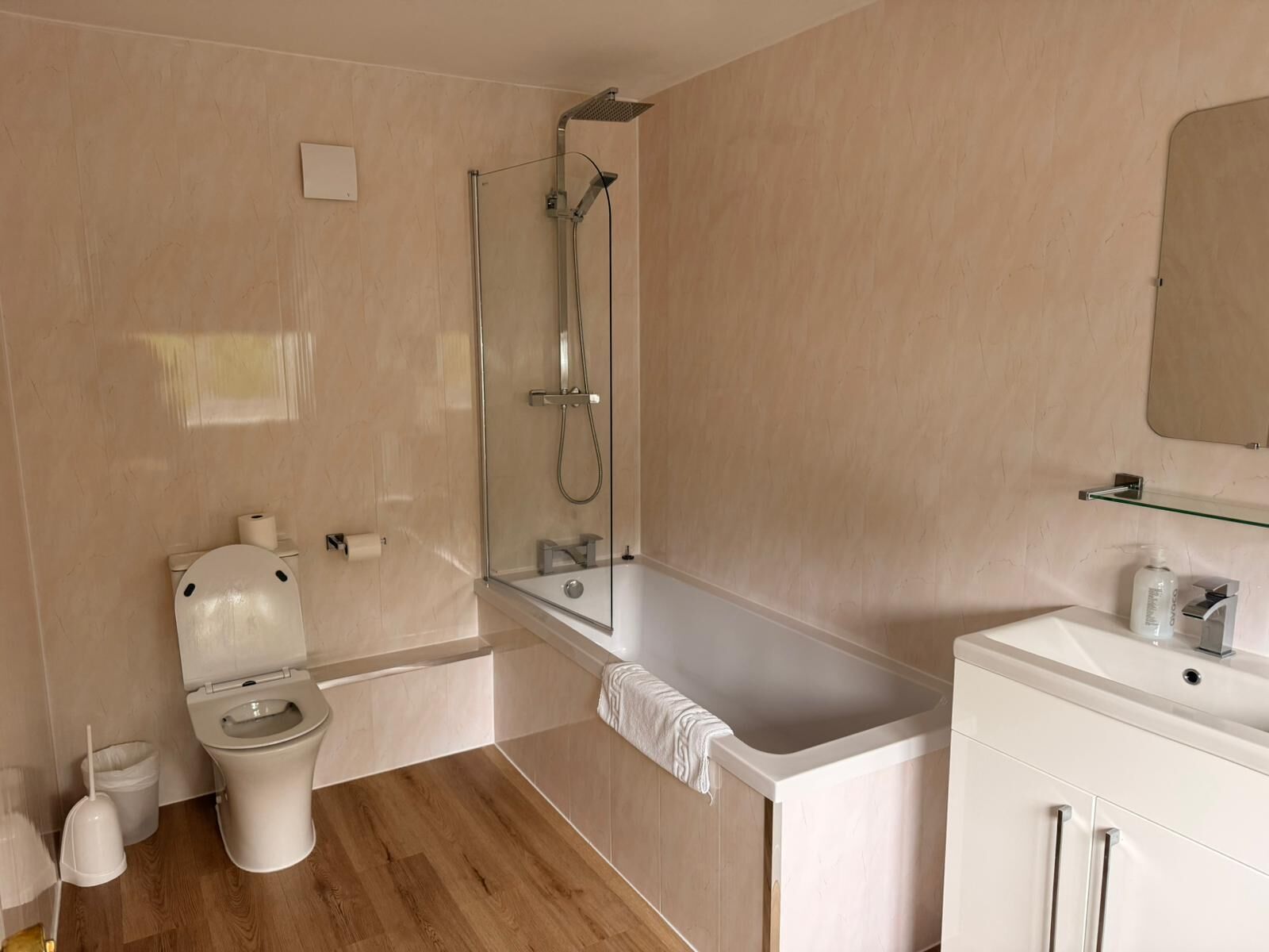 A modern bathroom with a toilet, shower, bathtub, and sink.