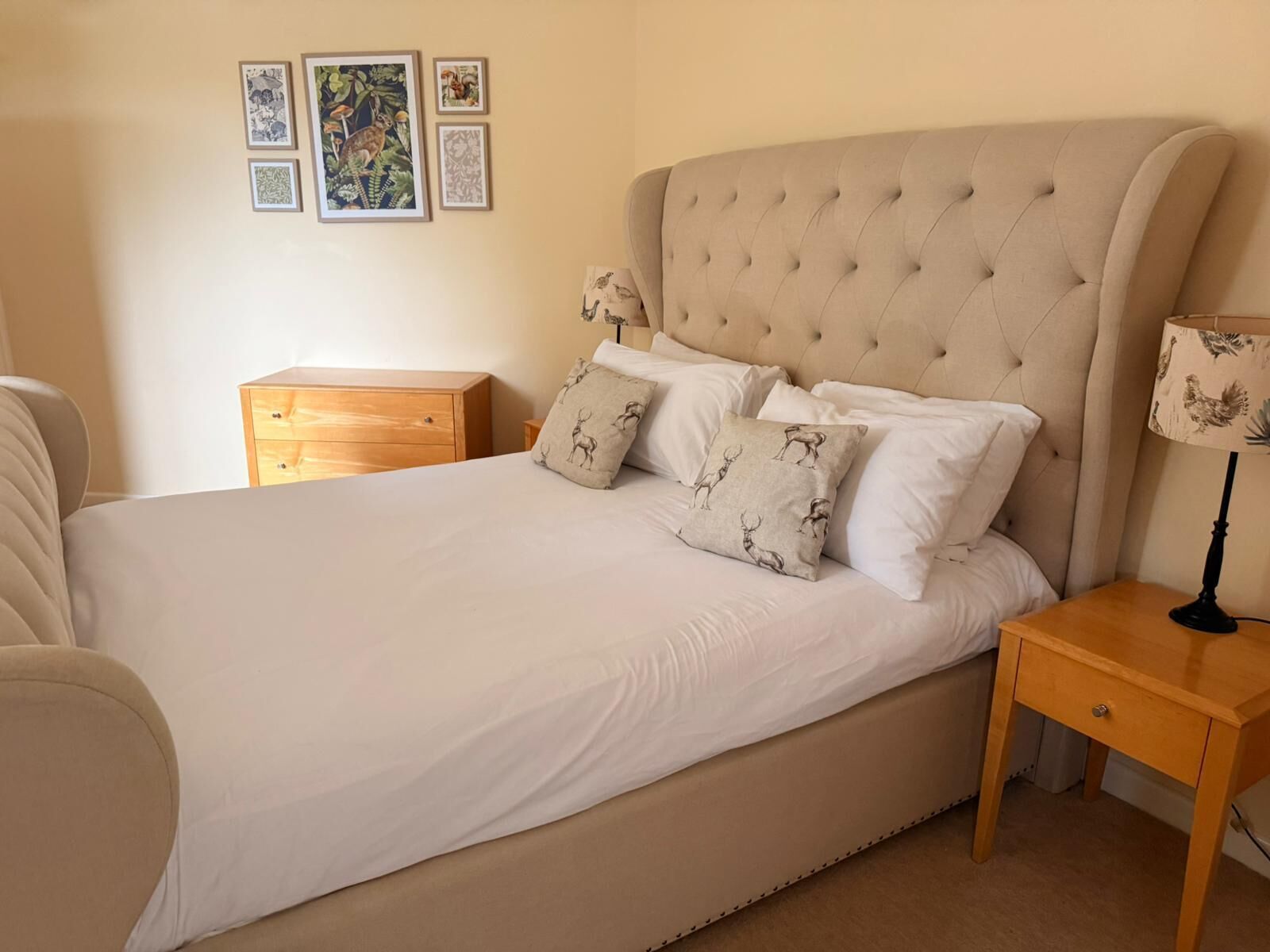 A neatly made bed with a tufted headboard, a bedside table with a lamp, and a wooden nightstand.