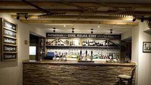 A bar area with a stone counter, various bottles, and a sign reading "DINE, RELAX, STAY".