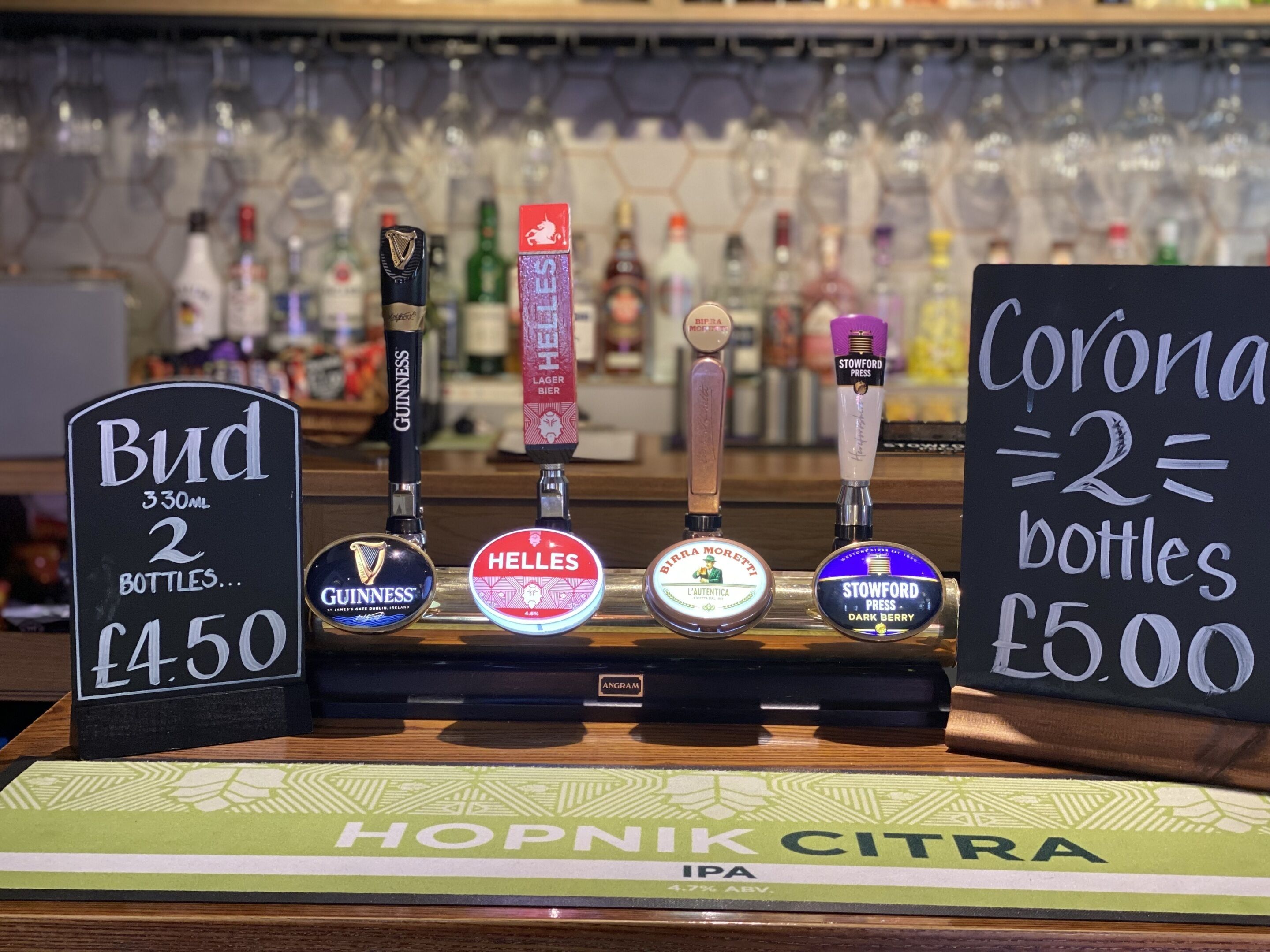 En bar med forskellige fadølshaner og et skilt, der tilbyder Bud 330ml til 2 flasker for 4,50 pund.