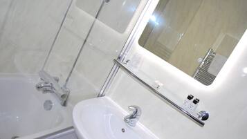 Een moderne badkamer met een glazen douchecabine, een witte wastafel en een spiegel.