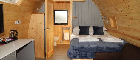 A cozy, compact room with a bed, a small desk, and a window.