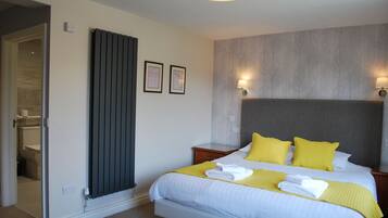 A hotel room with a bed, bedside lamps, a radiator, and a bathroom visible through an open door.