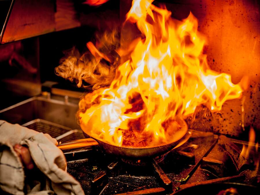 A close-up of a pan on a stove with flames.