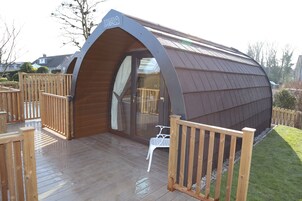 A modern, curved building with a wooden deck and a glass door entrance.