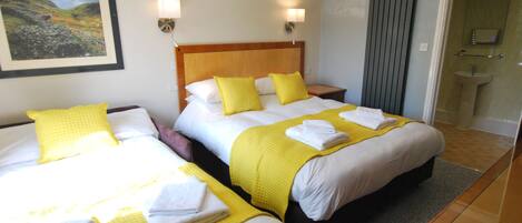 Una habitación de hotel con dos camas, cada una con ropa de cama amarilla y blanca, y un cuadro en la pared.