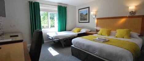 Une chambre d’hôtel avec deux lits, un bureau, une chaise, une fenêtre avec des rideaux et un tableau au mur.