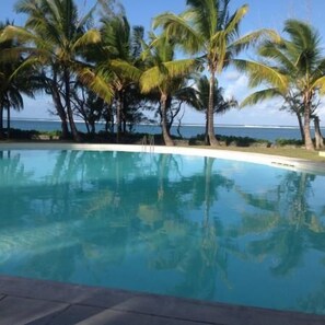 A clear pool with palm trees and a view of the ocean. - Thalassa Residence (Belle Mare)