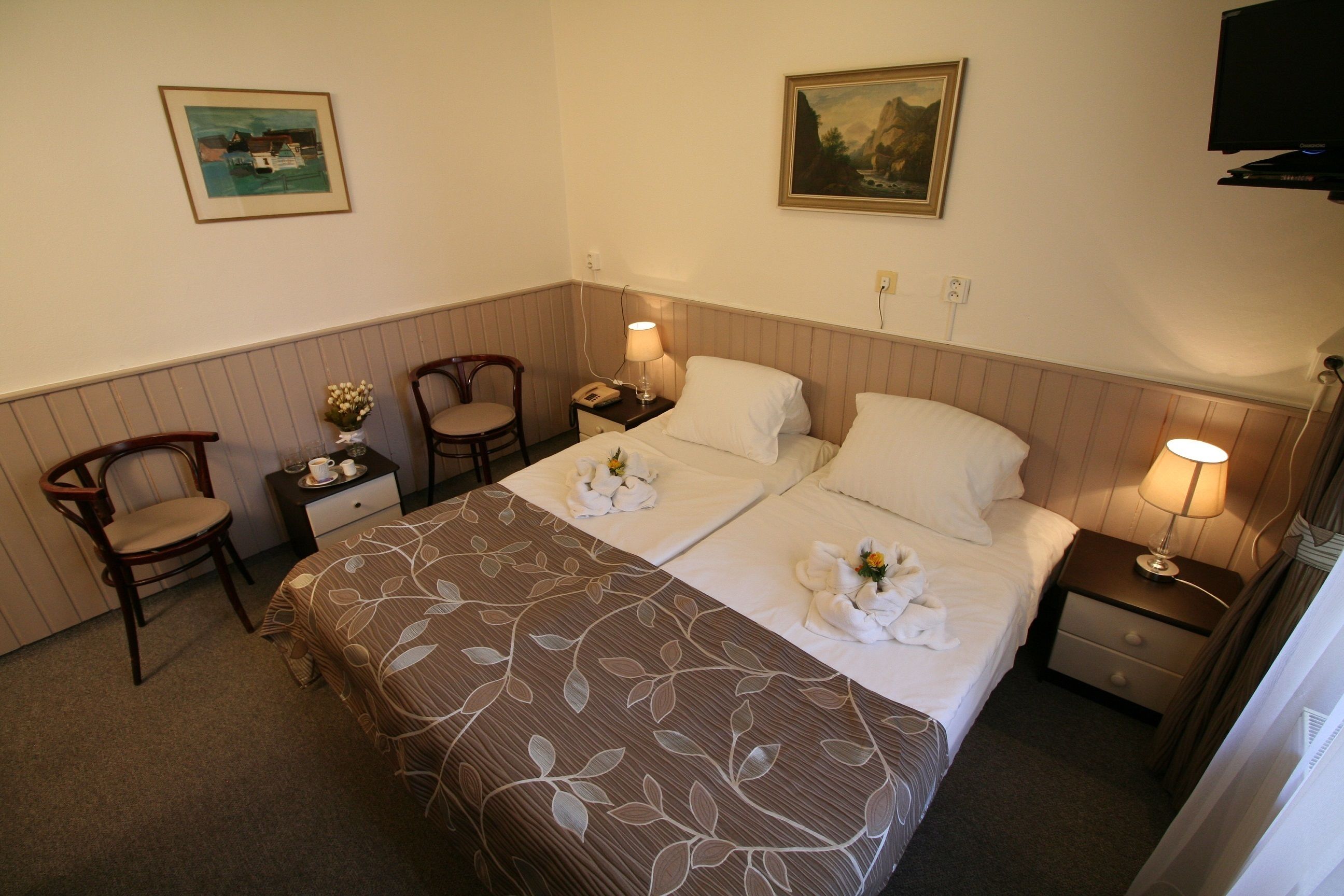 Une chambre d’hôtel avec deux lits, une chaise, une table de chevet et un téléviseur.