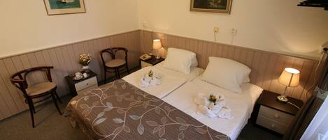 Une chambre d’hôtel avec deux lits, une chaise, une table de chevet et un téléviseur.