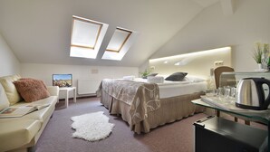 Quarto moderno com cama, sofá, mesa pequena e máquina de café.
